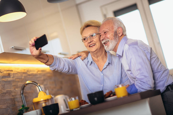 Smiling senior couple taking selfie at home - Photo, image