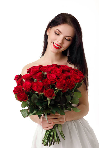 beautiful young woman with a large bouquet of red roses - Foto, Imagen