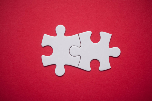 Primo piano di due pezzi puzzle collegati su sfondo rosso. Il concetto di trovare le giuste soluzioni nel lavoro di squadra
. - Foto, immagini