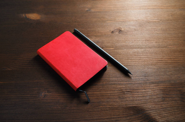 Red notepad and pencil on wood table background. Template for branding identity. - Fotoğraf, Görsel