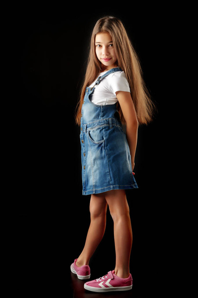 Little girl in denim clothes on a black background. - 写真・画像
