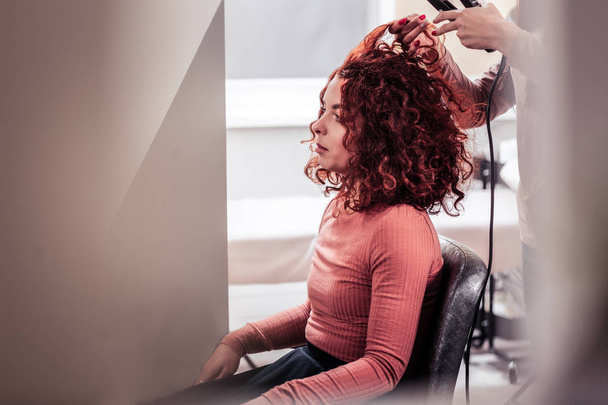 Nice red haired woman having her hair straightened - Photo, Image