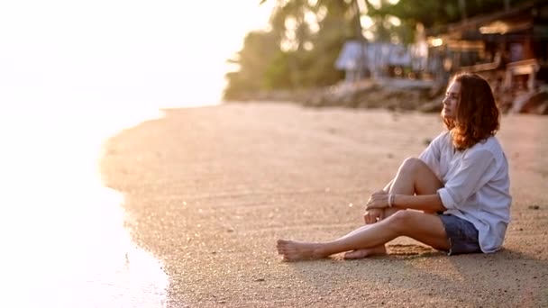 Onnellinen tyttö istuu meren rannalla odottamassa poikaystävänsä
. - Materiaali, video
