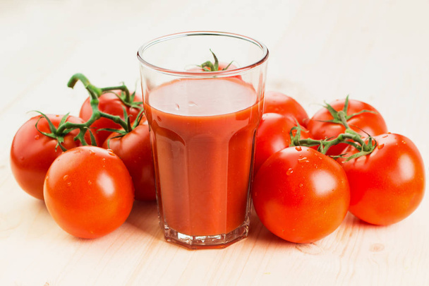 Glas Tomatensaft mit Tomaten auf Holzgrund, gesundes Lifestyle-Konzept. - Foto, Bild