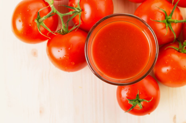 Glas Tomatensaft mit Tomaten auf Holzuntergrund, gesundes Lifestylekonzept. Kopierraum für Text. Blick von oben. - Foto, Bild