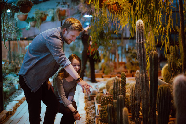 Ein verliebtes Paar geht durch das Gewächshaus. Liebhaber unter Evergreens im Wintergarten - Foto, Bild