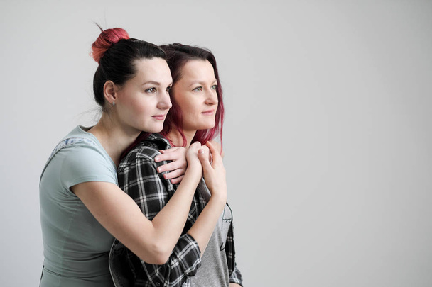 Two girls hug on a white background. Homosexual lesbian couple. Casual clothes. - Φωτογραφία, εικόνα