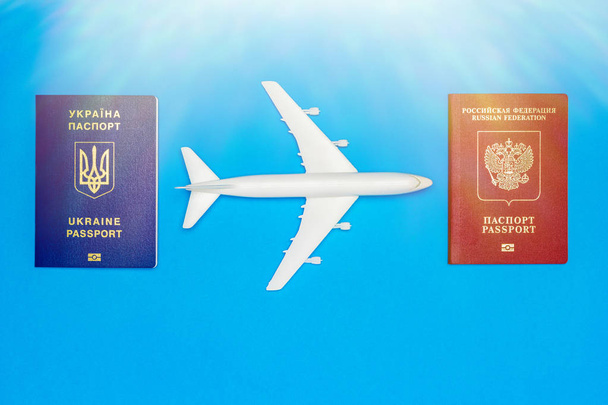 Українські та російські паспорти і моделі літака на синьому тлі. Концепція відновлення повітряних перевезень між країнами. - Фото, зображення