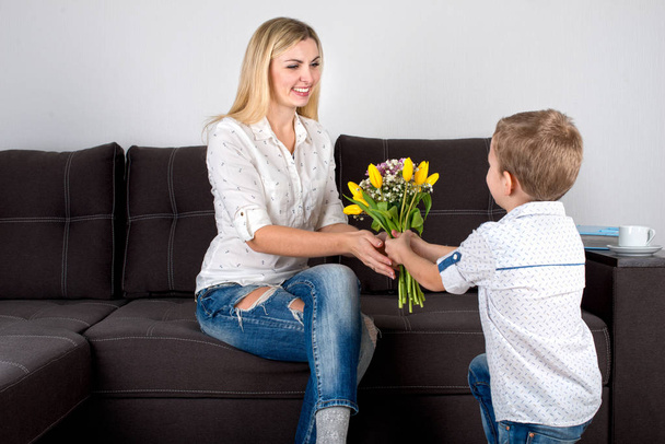 Son gives his beloved mother a beautiful bouquet of tulips.The concept of the celebration,women's day. - Photo, Image