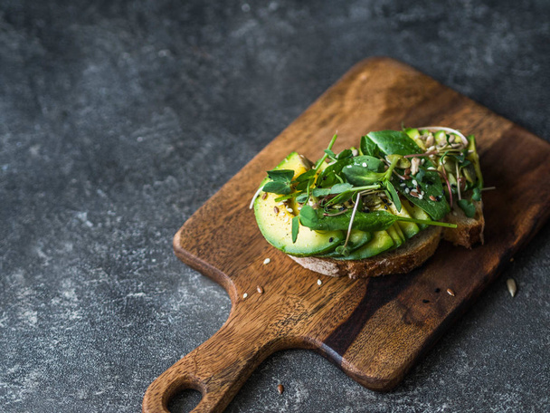 Green healthy sandwich made from spinach, sprouts, avocados and various seeds on a wood board - Fotografie, Obrázek