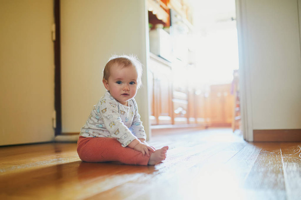 Baby girl sitting on the floor at home. Little child crawling at home and exploring the room - Fotoğraf, Görsel