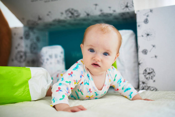 Suloinen vauva tyttö leikkii paperilaatikolla lastenhuoneessa
 - Valokuva, kuva
