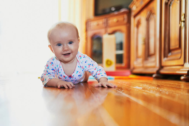 Baby girl learning to crawl. Happy healthy little child on the floor. Infant kid at home - Foto, Imagem