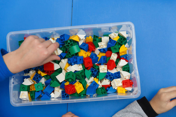 Close up of child's hands playing with colorful plastic bricks at the table. The first steps for the development of engineering type of thinking. - Photo, Image