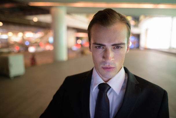 Face of young businessman outdoors at night - Valokuva, kuva