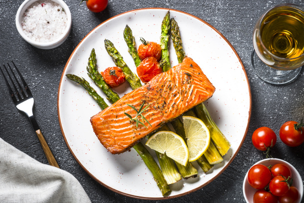 Baked salmon fish fillet with asparagus and tomato top view. - Photo, Image