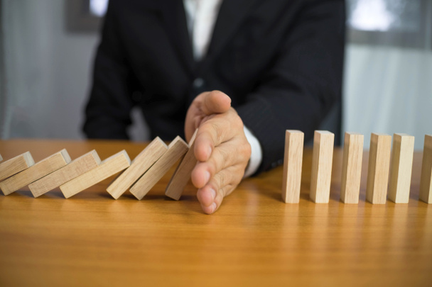 Businessman hand stops domino continuous overturned meaning that hindered business failure. Stop over this business failure concept. - Foto, Bild