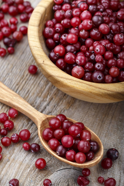 Fresh cranberries in a plate and in a spoon on a wooden table. space for tex - Foto, Bild