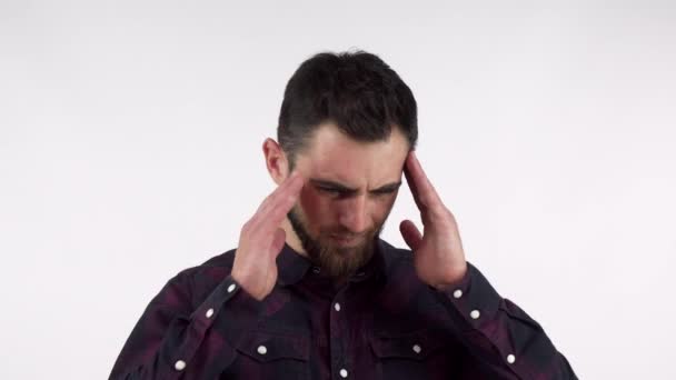 Bearded young man suffering from terrible headache, rubbing his temples - Footage, Video