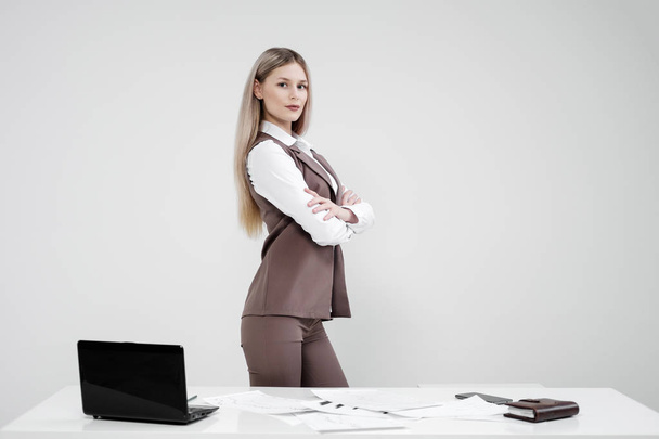 Blonde girl in a business suit works on a computer in a white bright office. - Foto, imagen