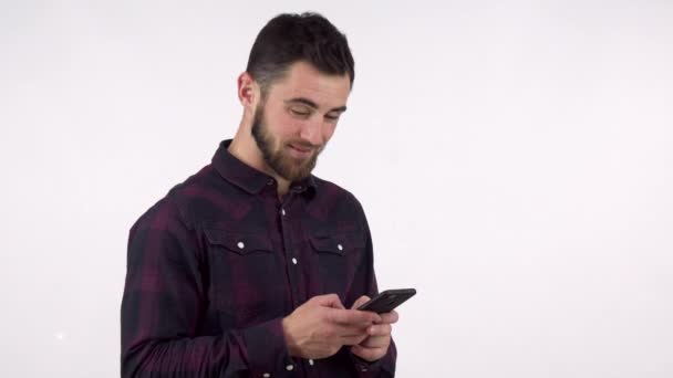Cheerful handsome bearded man using his smart phone, smiling joyfully - Materiał filmowy, wideo