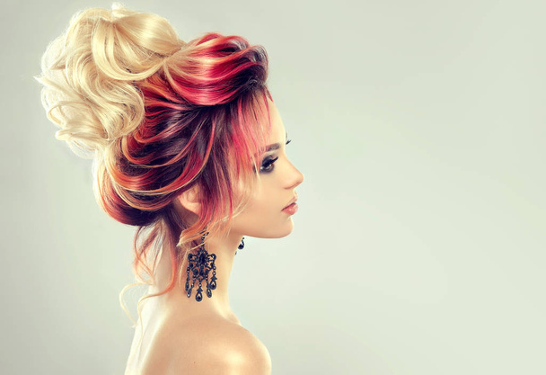Beautiful model girl with elegant multi colored hairstyle. Стильная женщина с модной подсветкой цвета волос. Творческие красные и розовые корни, модная окраска
. - Фото, изображение