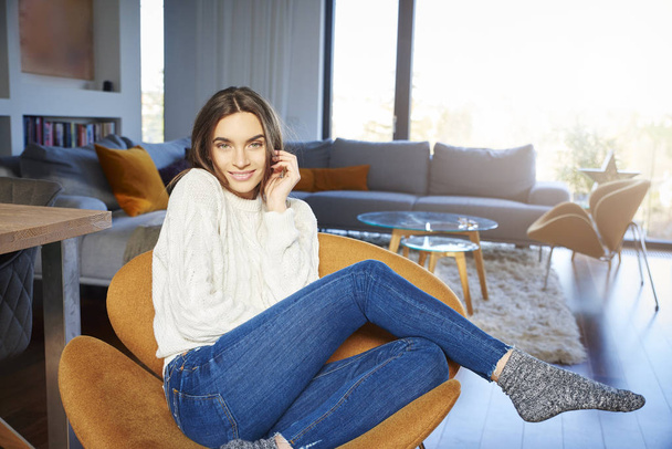 Portrait of young woman with beautiful smiling wearing casual clothes while relaxing in armchair at home.  - Foto, afbeelding