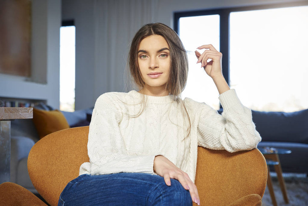 Portrait of young woman with beautiful smiling wearing casual clothes while relaxing in armchair at home.  - Foto, afbeelding