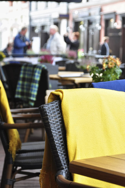 outside patio of an european restaurant - tables and black- brown chairs with yellow blankets for cold weather - Fotó, kép