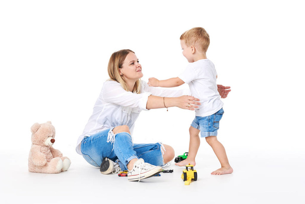 Happy young mother having fun with her toddler child - Son hugging his mum on white background - Family lifestyle, motherhood, love and tender moments concept - Foto, afbeelding