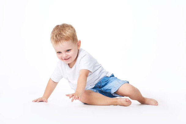 A cute little boy in a white T-shirt. The concept of promotional goods, inscriptions and drawings on clothes. Isolated on white background - 写真・画像