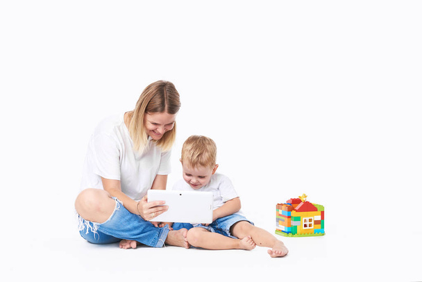 mother and kid play at tablet computer with toys at nursery on white isolated background. Play and fun - Фото, зображення