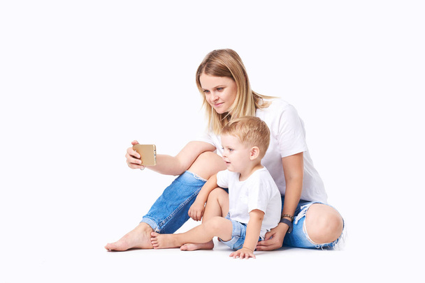 Happy mother laughing taking selfie with little son on smartphone, smiling single mom and cute adopted boy playing making photo posing for self portrait, mommy and kid watching video on cell  - Zdjęcie, obraz