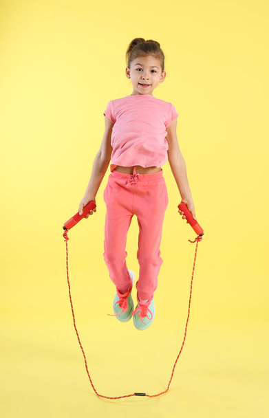 Full length portrait of girl jumping rope on color background - Photo, image