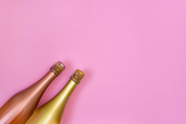 Two Champagne bottles on pink background. Copy space, top view. Flat lay of Christmas, anniversary, bachelorette, New Year celebration concept. - Photo, Image