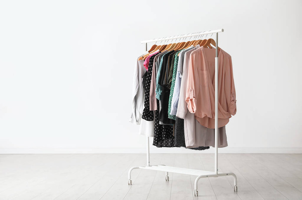 Wardrobe rack with stylish clothes near white wall indoors. Space for text - Фото, зображення