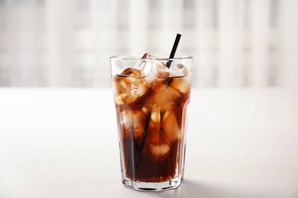 Glass of refreshing cola with ice on white table - Фото, зображення