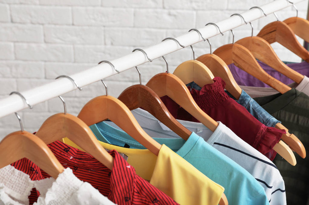 Wardrobe rack with stylish clothes near brick wall indoors, closeup - Фото, зображення