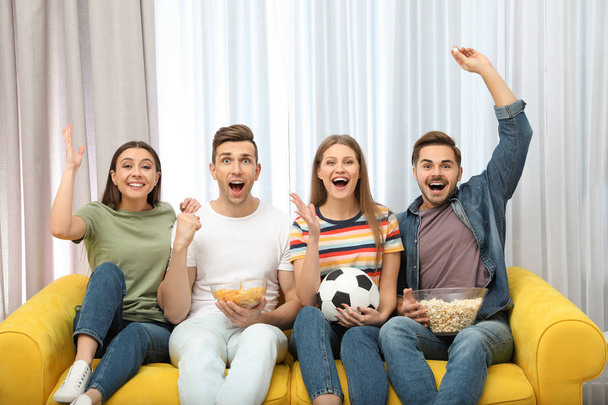 Group of people with snacks and ball watching soccer match on TV at home - Foto, imagen