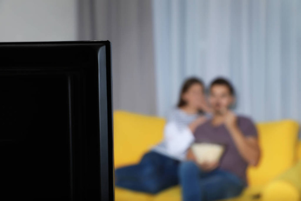 TV set and blurred couple on background. Space for text - Фото, изображение