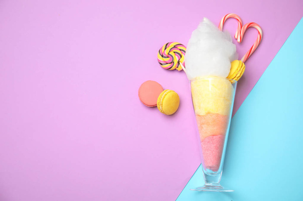 Composition with cotton candy in glass and space for text on color background, top view - Foto, Bild