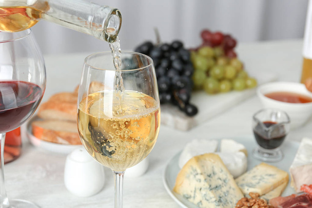 Pouring white wine into glass on served table. Space for text - Photo, image