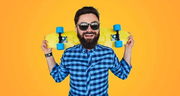 Hipster bearded man with a yellow skateboard - Foto, imagen