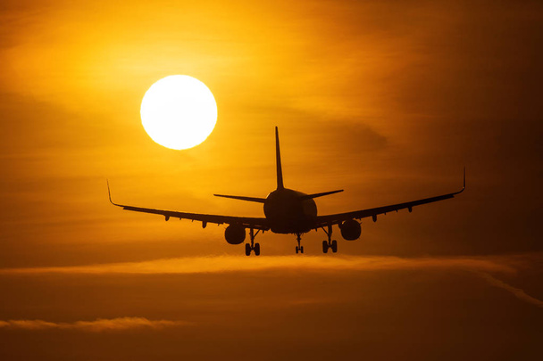 Силуэт воздушного самолета рядом с солнцем с красивыми красными облаками на заднем плане
 - Фото, изображение