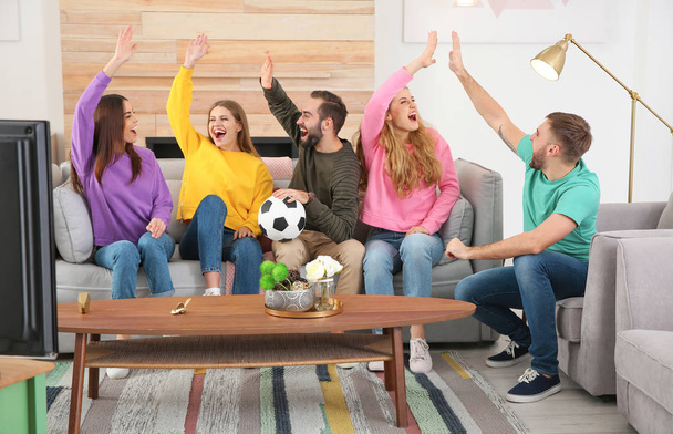 Group of friends celebrating victory of favorite soccer team in living room - Foto, Imagem
