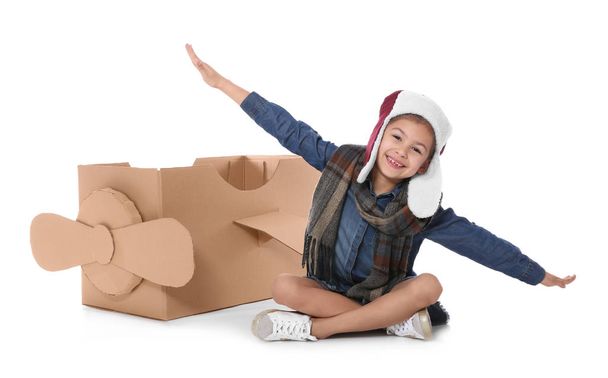 Cute little girl playing with cardboard airplane on white background - Фото, зображення
