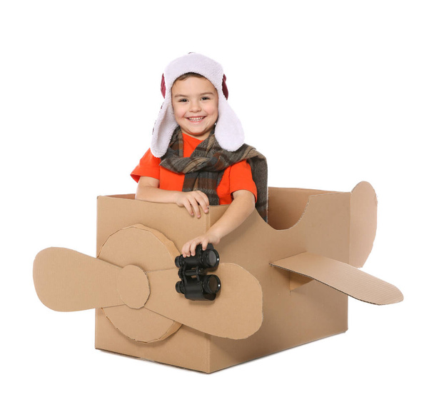 Cute little boy playing with binoculars and cardboard airplane on white background - Photo, Image
