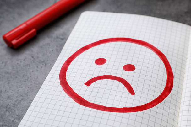 Notebook with drawing of unhappy face on table, closeup. Depression symptoms - Photo, Image