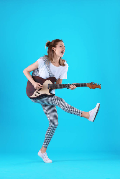 Young woman playing electric guitar on color background - Fotó, kép