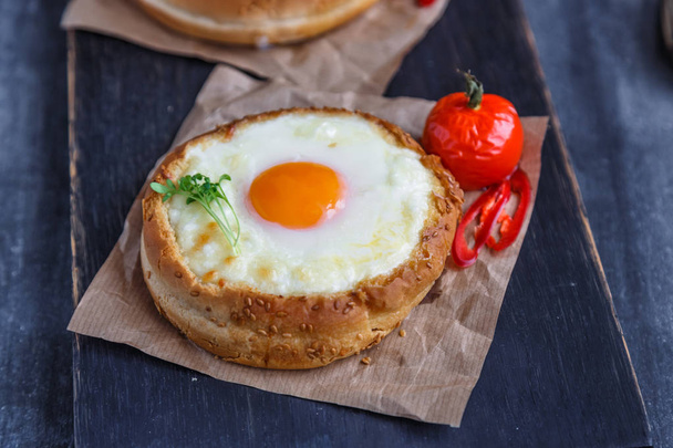 Brioche relleno de queso con yema de huevo y tomate al horno
. - Foto, imagen